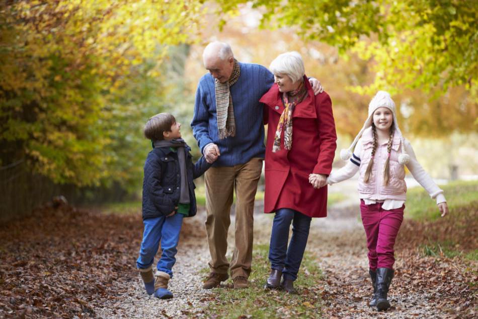 Grandparents With Grandchildren Walking Along Autumn Path